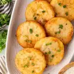 Platter of golden fried grit cakes garnished with fresh parsley for the Grit Cakes Recipe