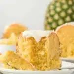 A slice of Pineapple Pound Cake Recipe on a white plate with a fork, showing its moist interior and glaze