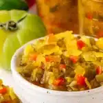 Bowl of homemade chow chow relish with jars and fresh vegetables in the background