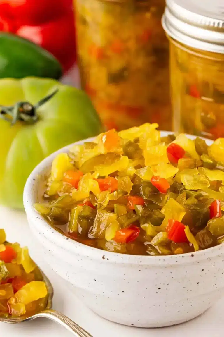 Bowl of homemade chow chow relish with jars and fresh vegetables in the background