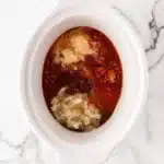 Slow Cooker Shredded Chicken Recipe ingredients and barbecue sauce base in a white slow cooker