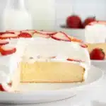 The BEST Strawberry Cheesecake Shortcake with a slice removed revealing moist cake, cheesecake, and whipped cream layers