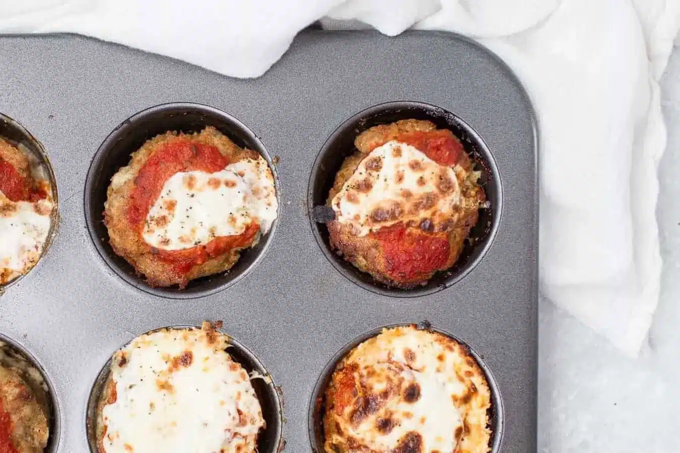 Baked turkey meatloaf muffins with tomato sauce and cheese in a muffin tray