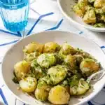 Vinegar-Based French Potato Salad with Cornichons 2 A plated serving of French potato salad with a fork, ready to eat