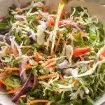 Vinaigrette dressing being poured over vegetable slaw